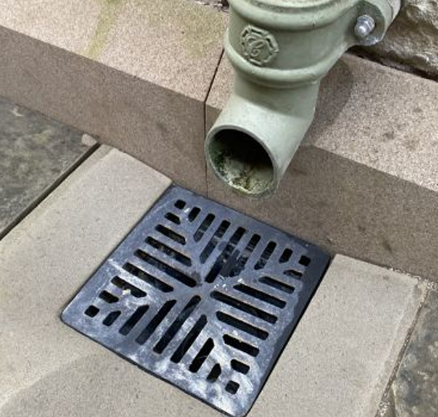 A picture of a gully grid and drain pipe