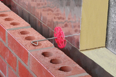 Picture of a wall tie being placed into a wall