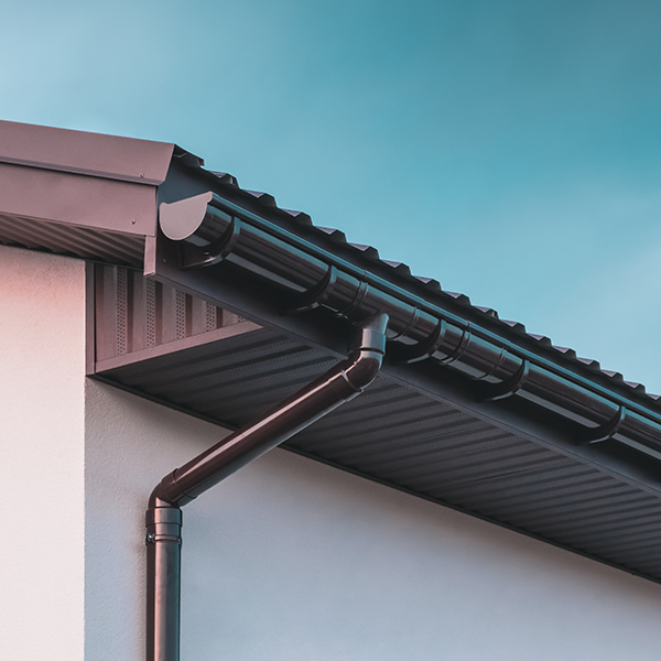 Black gutter and downpipes attached to a roof